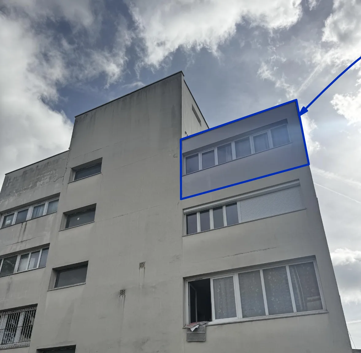 Photographie de l'immeuble en béton enduit, le troisième étage concerné par le changement de destination étant encadré en bleu ; façades inchangées.