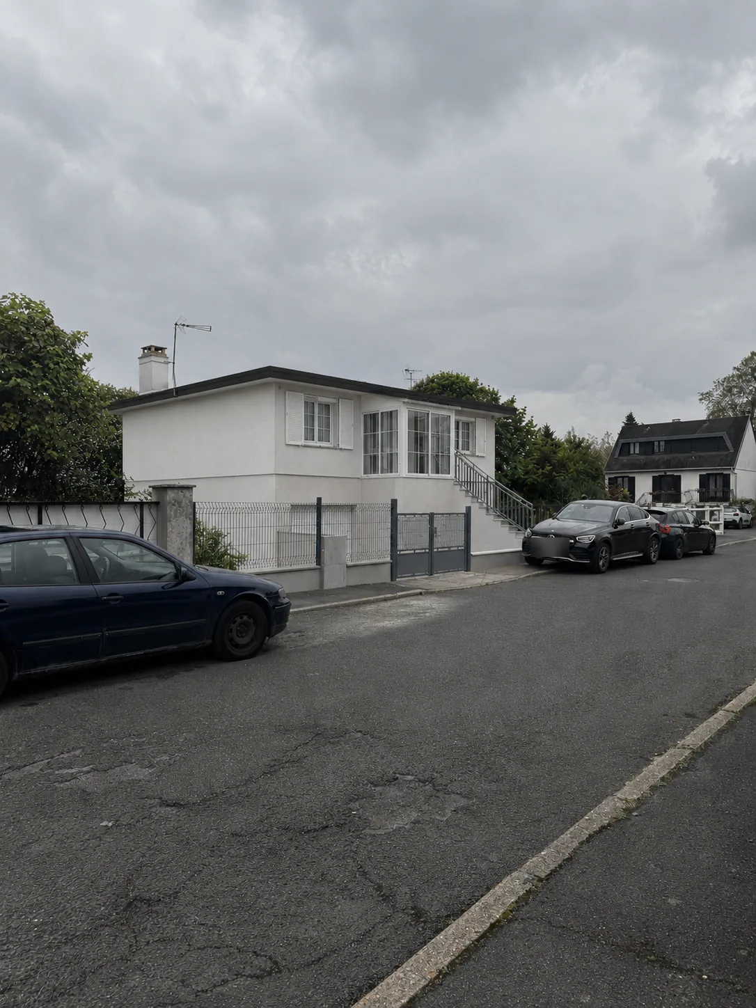 Photomontage depuis la rue montrant la maison blanche avec la nouvelle véranda d'entrée vitrée en haut de l'escalier extérieur.